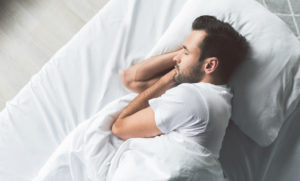 Cute young man sleeping on bed